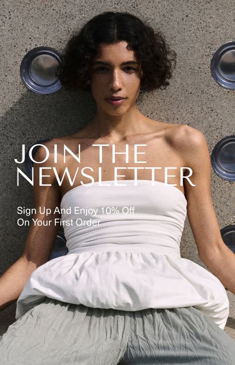 Woman in a white strapless dress sits against a textured wall with circular patterns, promoting newsletter signup for 10% off first order.