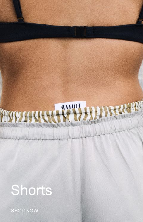 A person in a black bikini top and striped shorts with an "EDITED" label. Text at the bottom reads "Shorts, SHOP NOW."