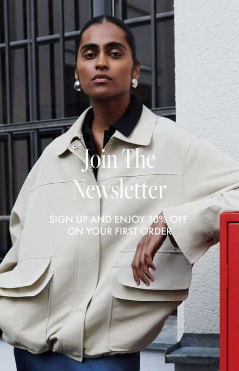 Person in a light coat stands confidently by a red postbox in front of a building. Text reads: "Join The Newsletter."