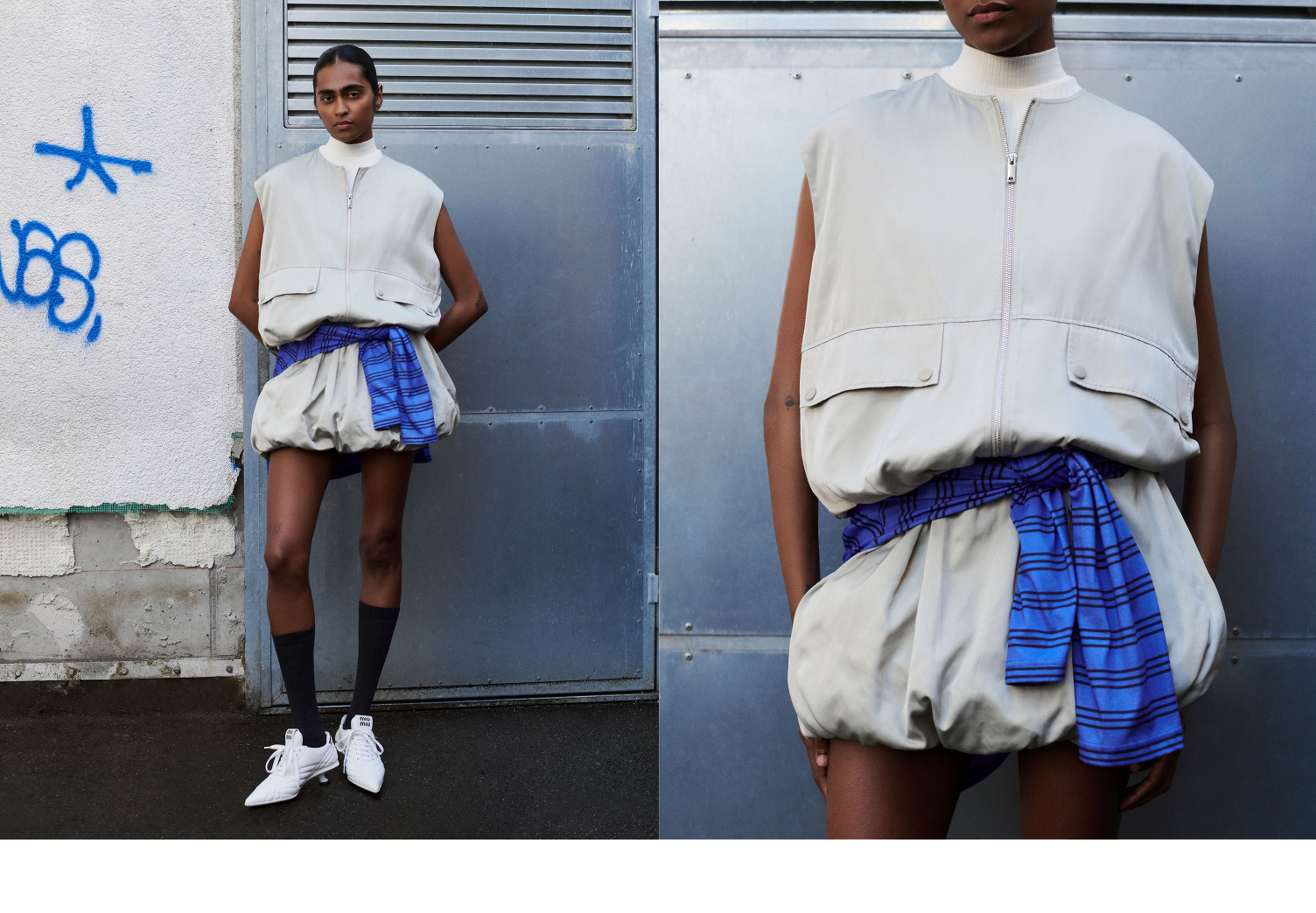 Model in a sleeveless, beige, oversized zipped vest with pockets, and a blue plaid wrap skirt, standing against an urban, graffiti-covered backdrop.
