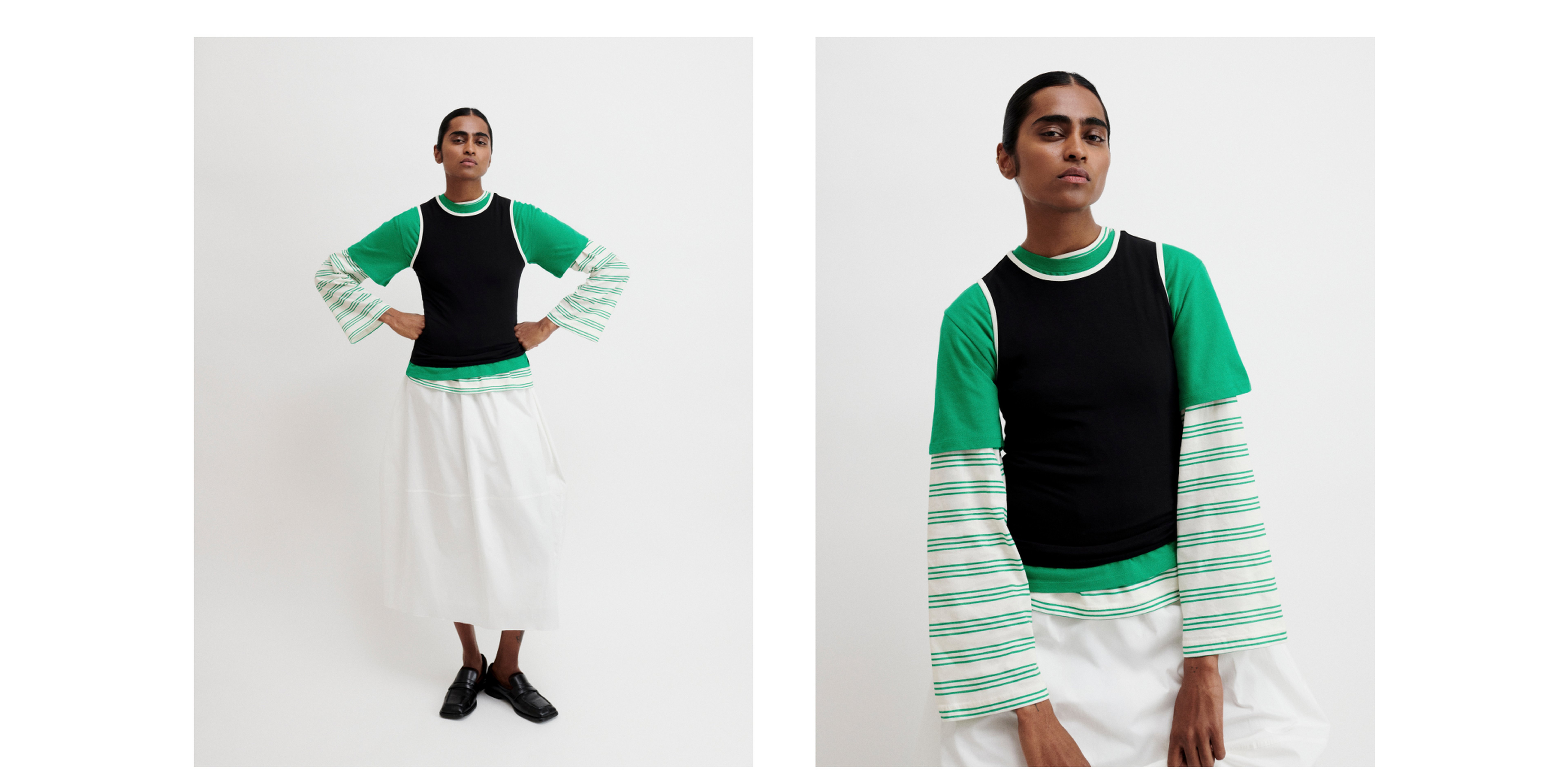 Person posing in a green shirt with striped sleeves, black vest, white skirt, and black shoes against a plain background.