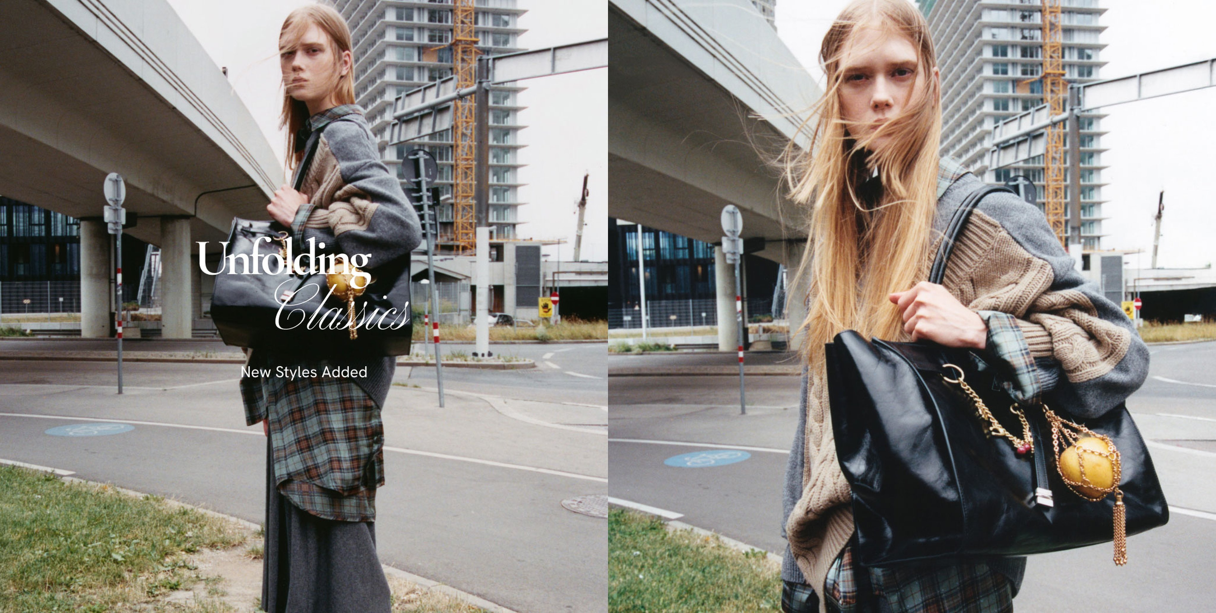 A person with long hair in layered clothing stands outdoors near an overpass, holding a black bag with decorative items. Urban background.