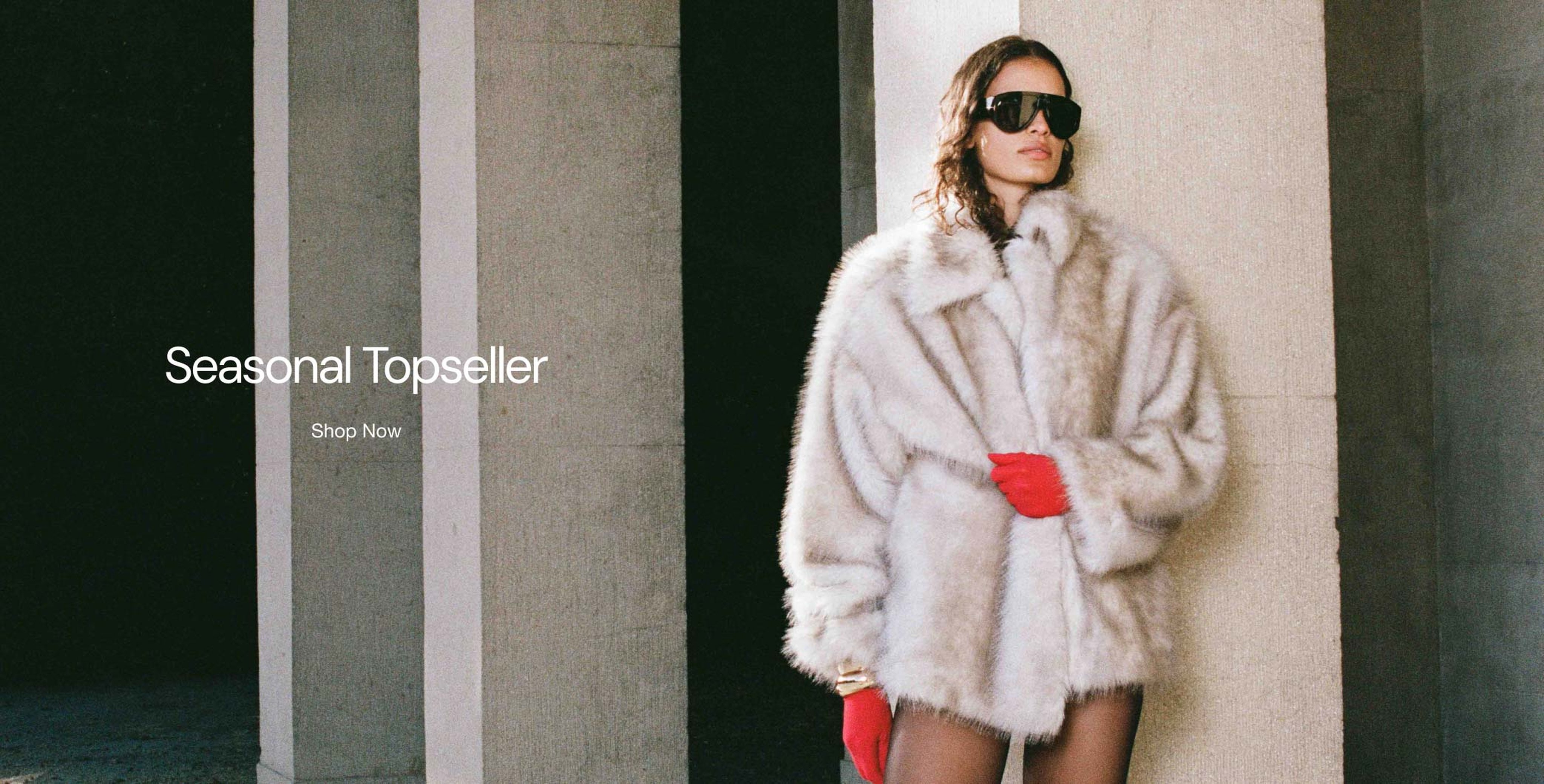 Person wearing a white fur coat, red gloves, and sunglasses stands near columns. Text reads "Seasonal Topseller - Shop Now."