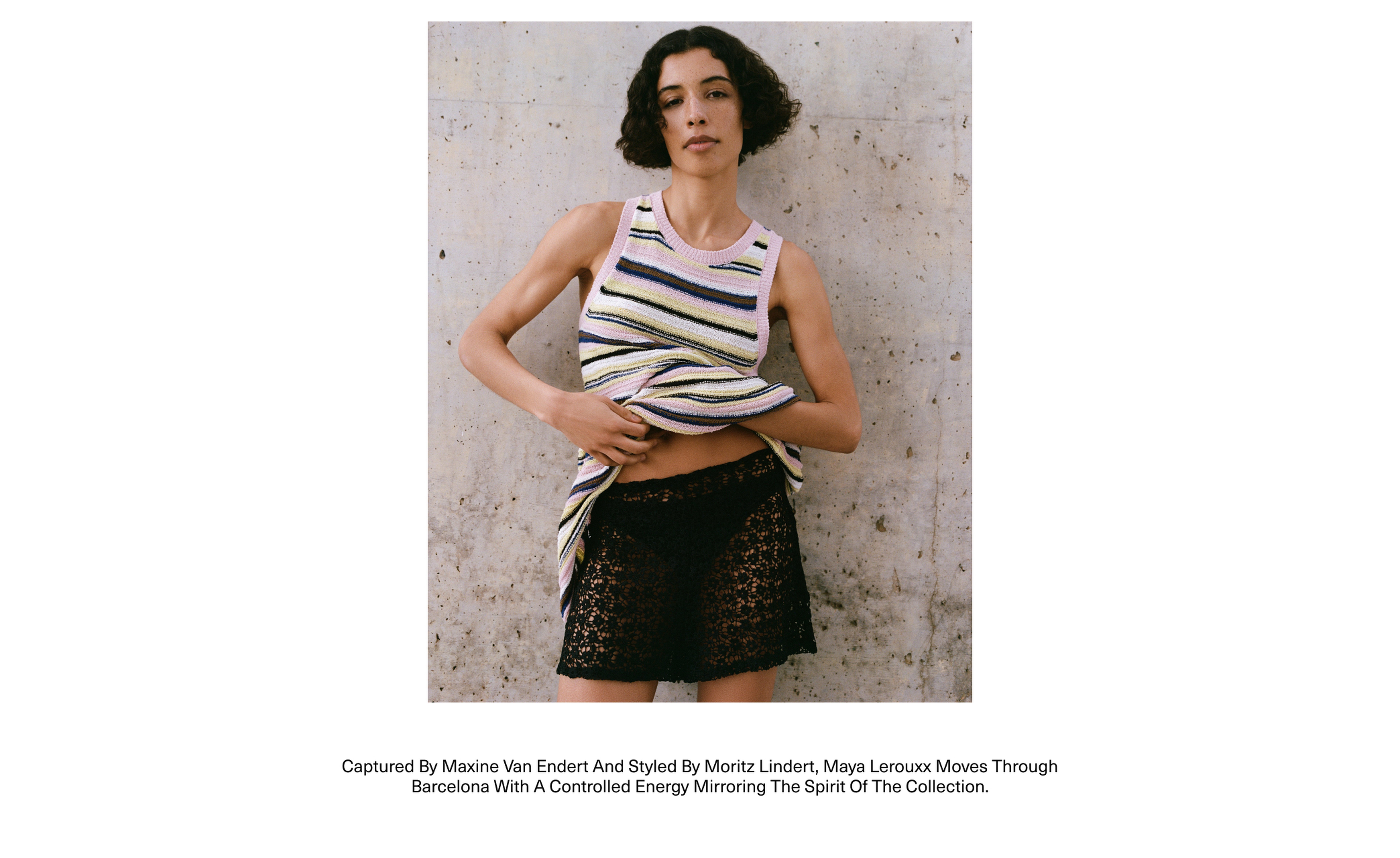 Person in a striped tank top and lace shorts stands confidently against a textured wall, showcasing a relaxed and stylish pose.