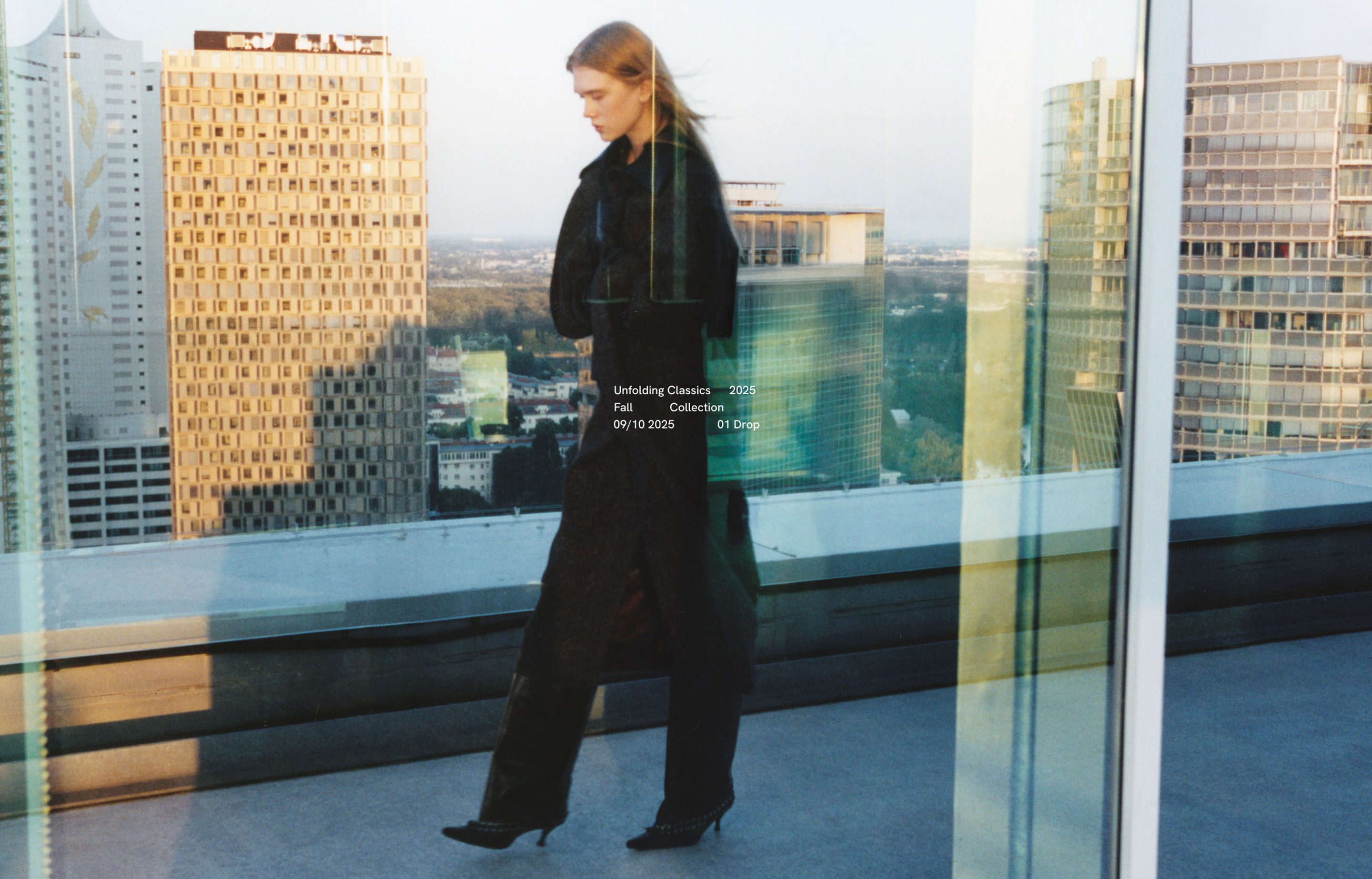 Woman in black outfit walking on a rooftop with cityscape in the background, glass reflections creating a layered effect.