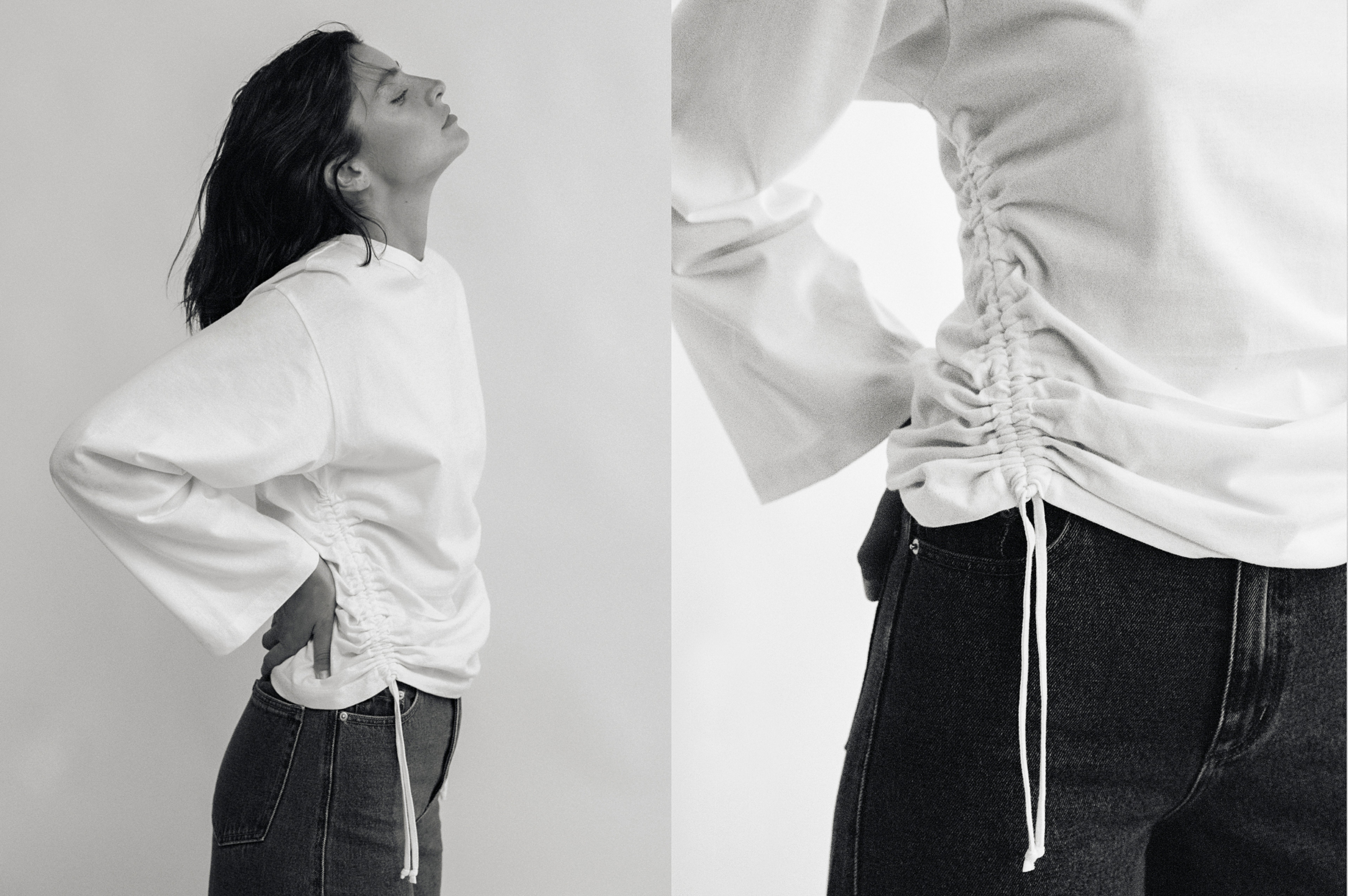 A black and white image of a person wearing a white top with ruched sides paired with dark jeans, shown in a profile pose and close-up.