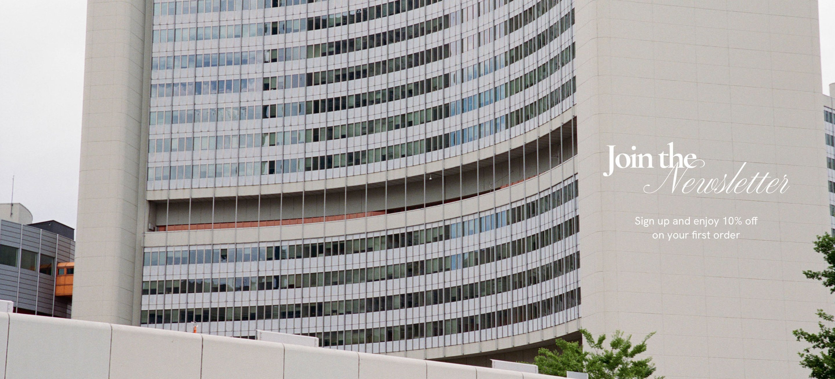 Curved modern building with glass windows, featuring text: "Join the Newsletter. Sign up and enjoy 10% off on your first order."