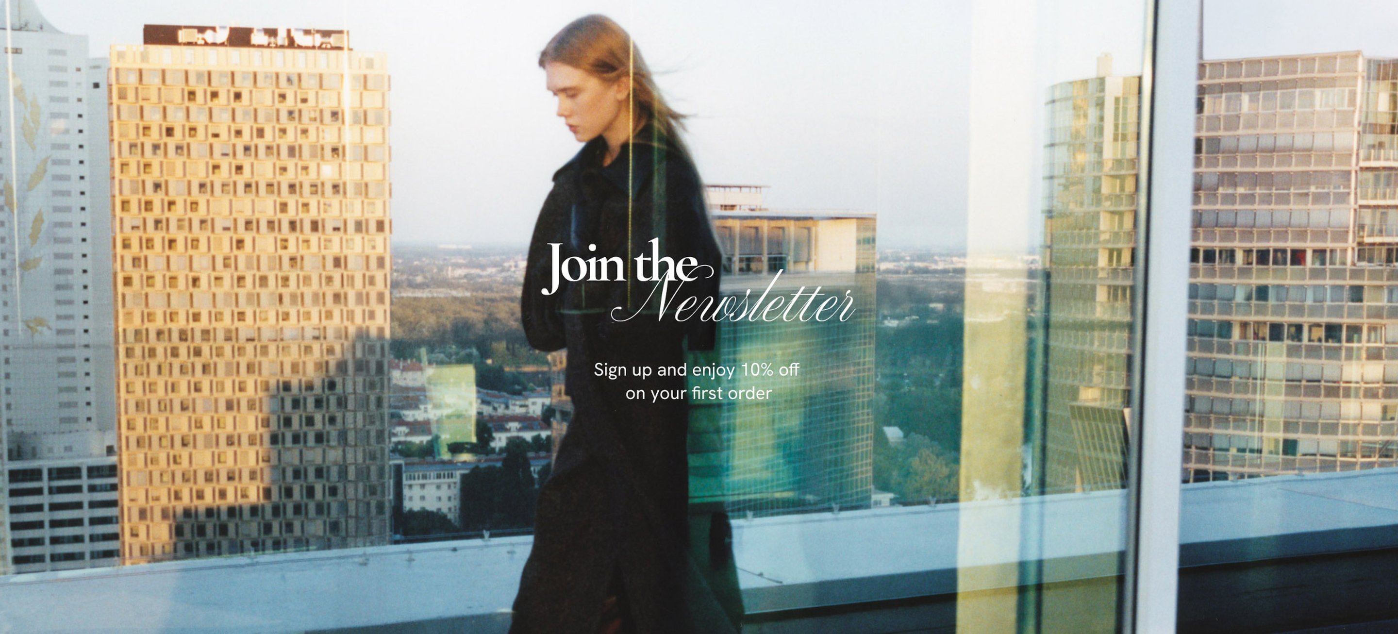 Woman in a long coat walking on a rooftop with cityscape background, text overlay reads "Join the Newsletter" offering 10% off first order.