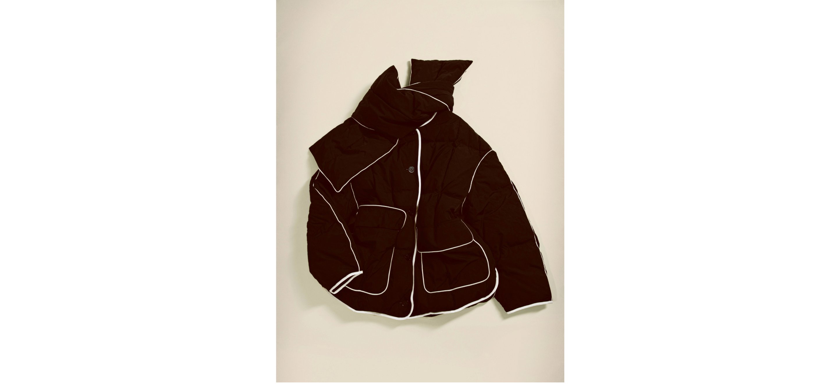 Black puffer jacket with white piping, featuring multiple pockets, displayed against a light background.
