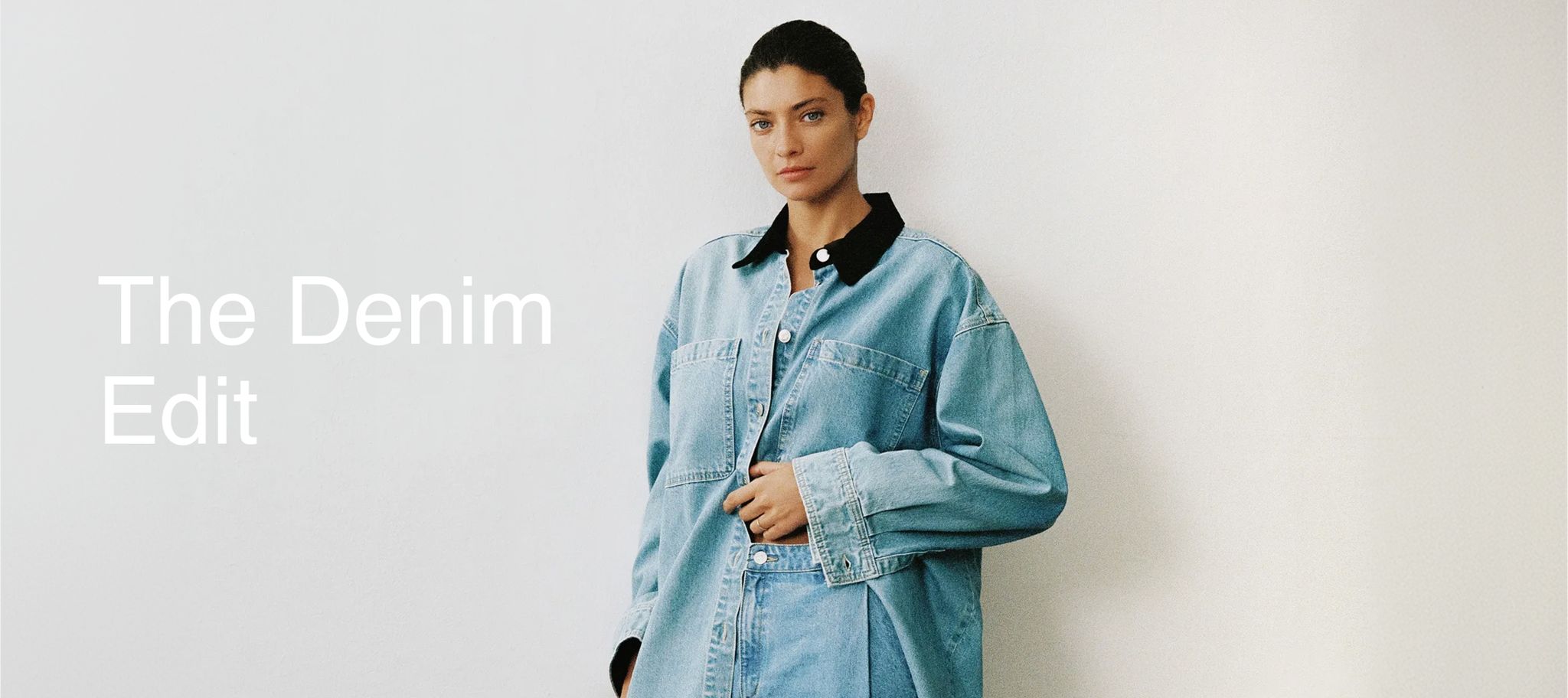 Person wearing an oversized denim jacket with text "The Denim Edit" on a plain background.