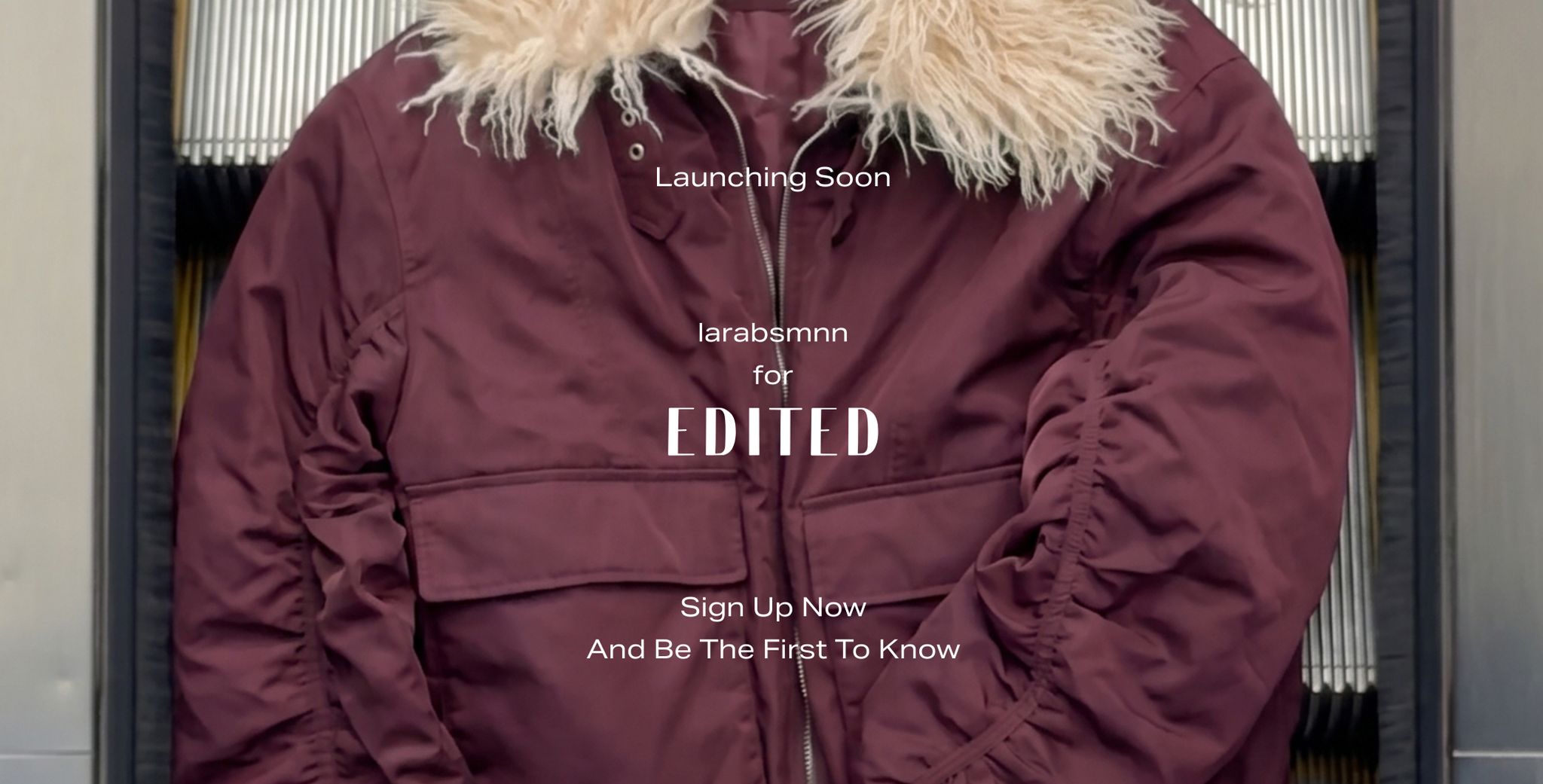 Maroon parka with a fluffy collar, text overlaying the jacket says "Launching Soon," promoting a collaboration and sign-up opportunity.