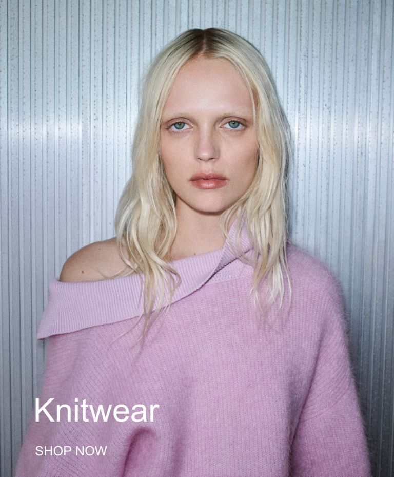 A person wearing a light pink off-the-shoulder knit sweater stands against a ribbed metallic background with text "Knitwear" and "SHOP NOW".