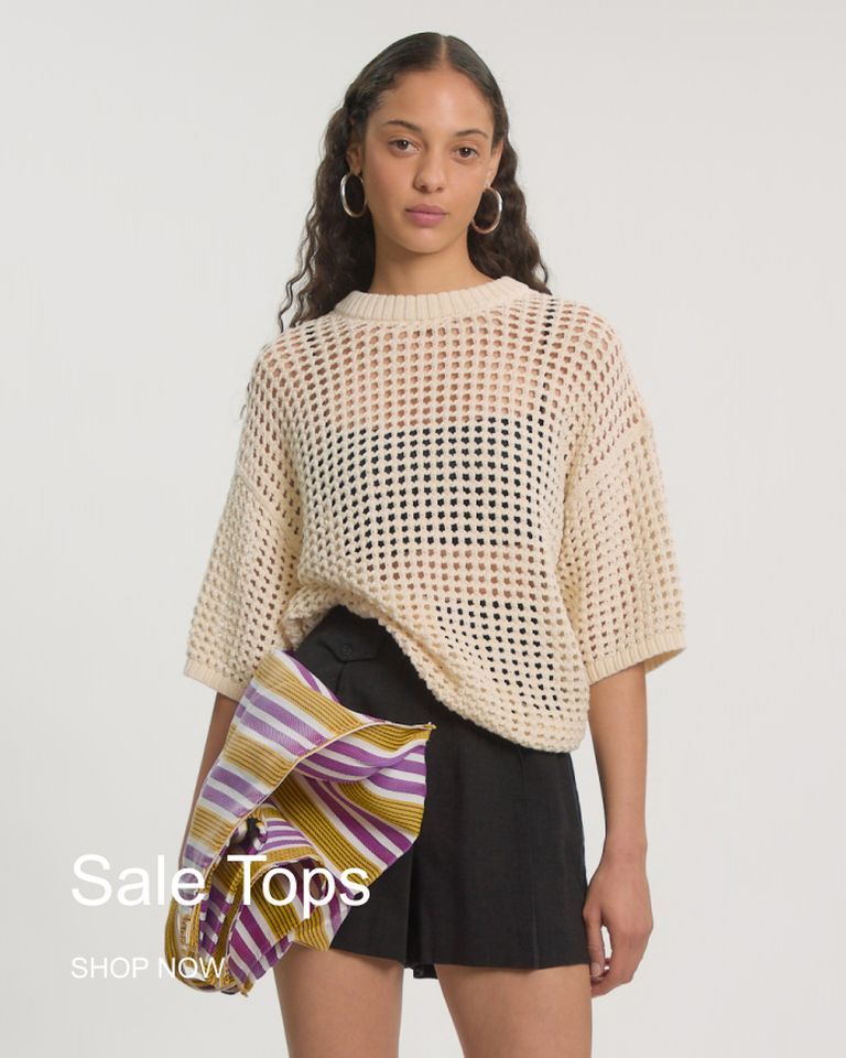Woman in a cream crochet top and black shorts, holding a striped bag, with text "Sale Tops" and "Shop Now" on a plain white background.