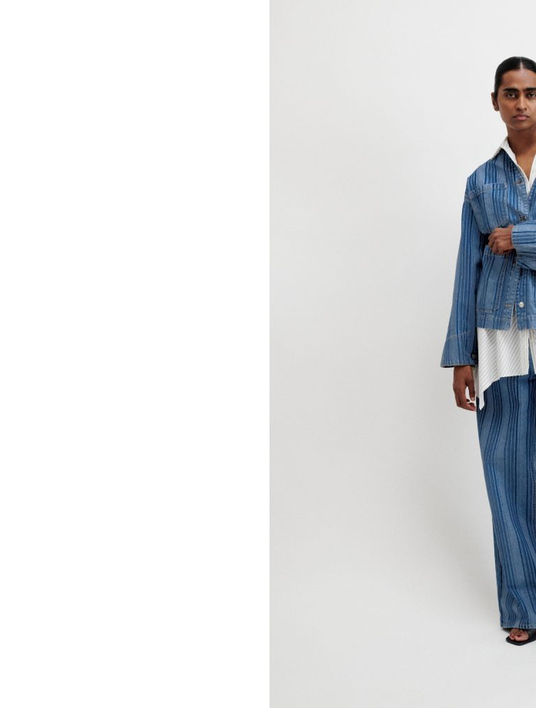 Person wearing a blue pinstripe suit over a white shirt, standing against a plain white background.