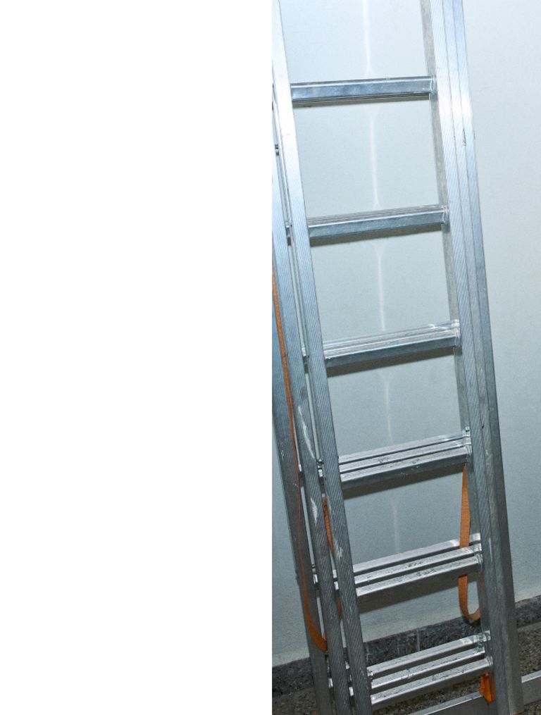 A metal ladder leaning against a white wall, with orange straps on the sides, standing on a dark speckled floor.