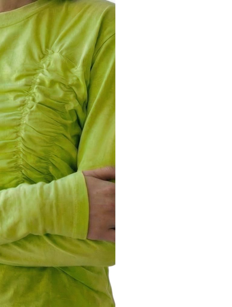 Person in a bright yellow-green shirt with ruched fabric, arms crossed.