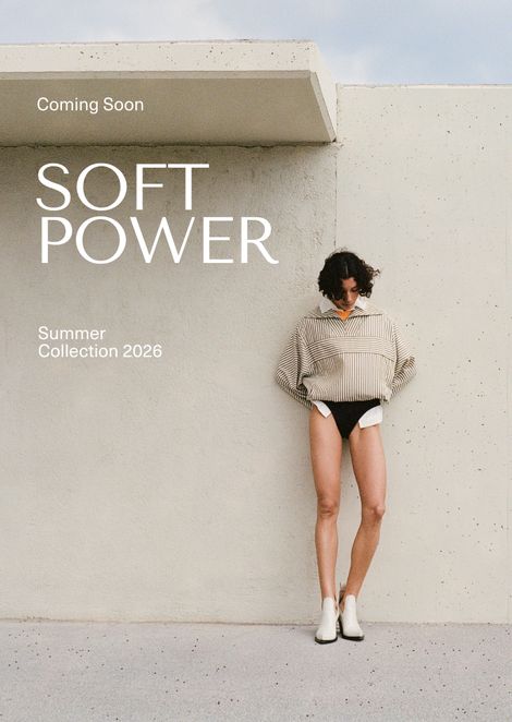 Person in a striped sweater and black bottoms stands against a concrete wall. Text: "Soft Power, Summer Collection 2026, Coming Soon."