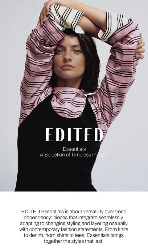 Woman in a black dress with pink striped sleeves, arms raised, modeling for Edited Essentials clothing line.