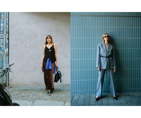 Two women in stylish outfits: one in a sleeveless black top and skirt with a blue jacket; the other in a gray suit with black accessories.