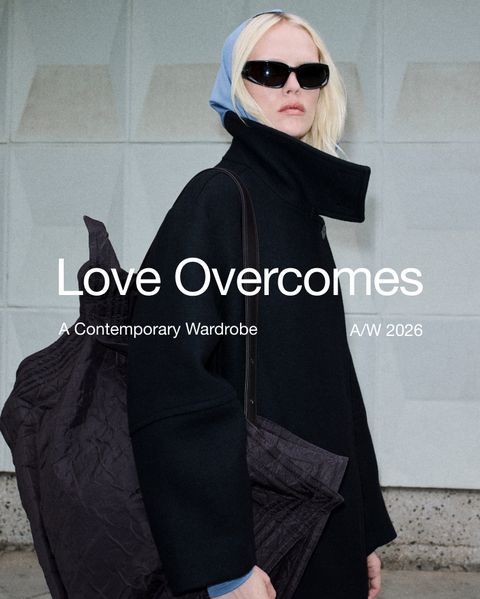 Person in a black coat and sunglasses, carrying a large textured bag, with text reading "Love Overcomes, A Contemporary Wardrobe, A/W 2026."