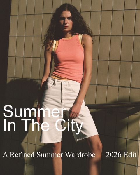 Woman in a pink tank top and white shorts stands against a tiled wall. Text reads: "Summer In The City, A Refined Summer Wardrobe, 2026 Edit."
