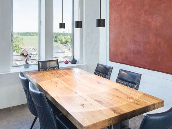 Modernes Esszimmer mit einem Holztisch, sechs blauen Stühlen, großem roten Wandbild, hohen Fenstern und OCULUS Pendelleuchten.