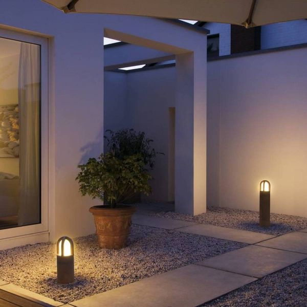 Moderne Terrasse mit sanfter Beleuchtung durch RUSTY® CONE und Topfpflanzen bei Nacht.