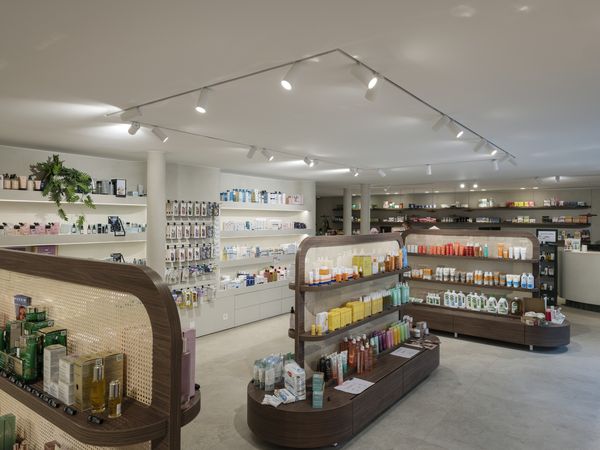 Ein geräumiges, helles Geschäft mit übersichtlichen Regalen, in denen eine Auswahl an Kosmetik- und Hautpflegeprodukten präsentiert wird. Beleuchtet durch 48-V-NUMINOS®-Strahler in Weiß.