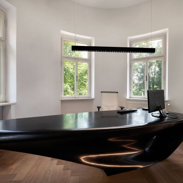 Modern office with a sleek black desk, white chair, computer monitor, large windows, and GLENOS® PRO pendant light.