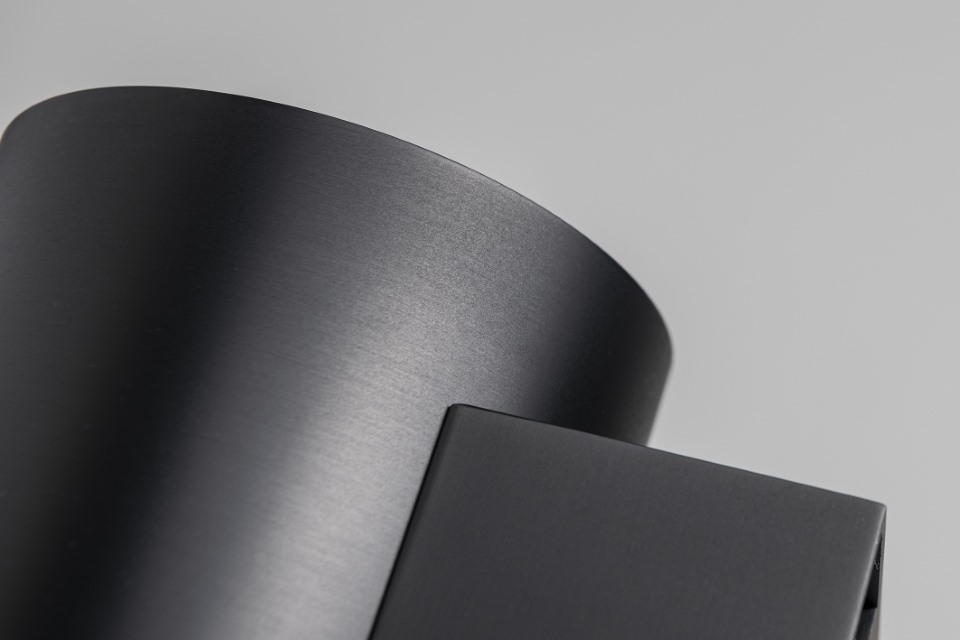 Close-up of a sleek, modern metallic cylindrical object with a matte finish against a light gray background.