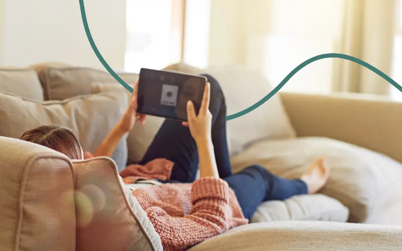 Kvinde ser en film p&aring; sin tablet i sofaen
