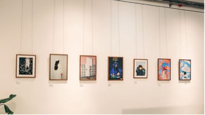 A series of framed photographs hang on a gallery wall. Each image is uniquely styled and vibrant, with minimalistic labels beneath.