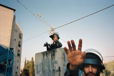 A person in riot gear gestures with an open hand