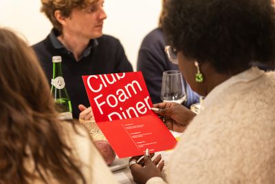 Person sitting at a table, reading a Club Foam Diner flyer
