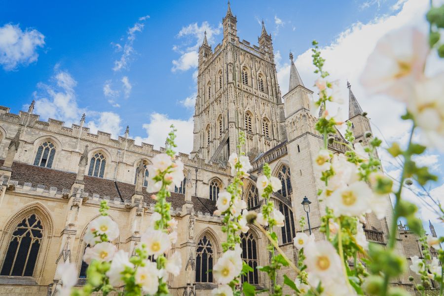 Gloucester Cathedral under a blue sky with flowers in front