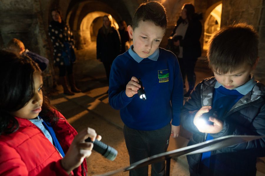 school children exploring the crypt with a torch
