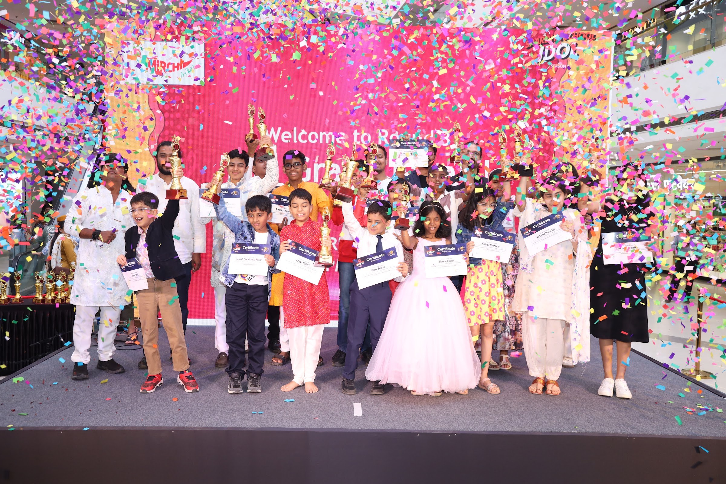 Winners celebrating on stage with trophies, certificates, and confetti at School Idol 2026