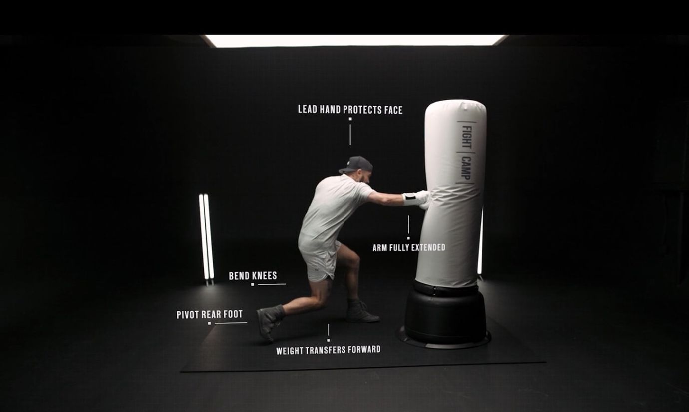 Man in a boxing stance punching a heavy bag labeled with technique tips like bending knees and extending the arm.