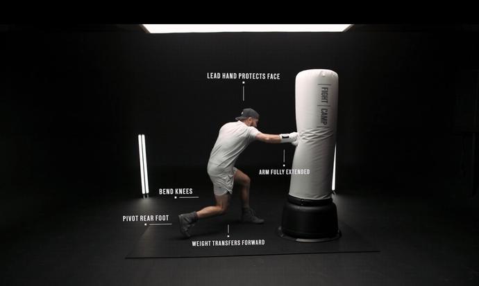 Man in a boxing stance punching a heavy bag labeled with technique tips like bending knees and extending the arm.