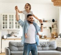 A father and daughter celebrating in the living room of their new house