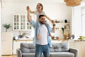 A father and daughter celebrating in the living room of their new house