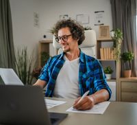 A man on his laptop looking at smsf loans in his home filling out paperwork