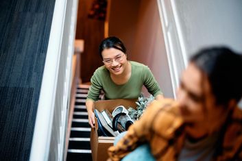 Two female roomates moving into their rental walking up the stairs