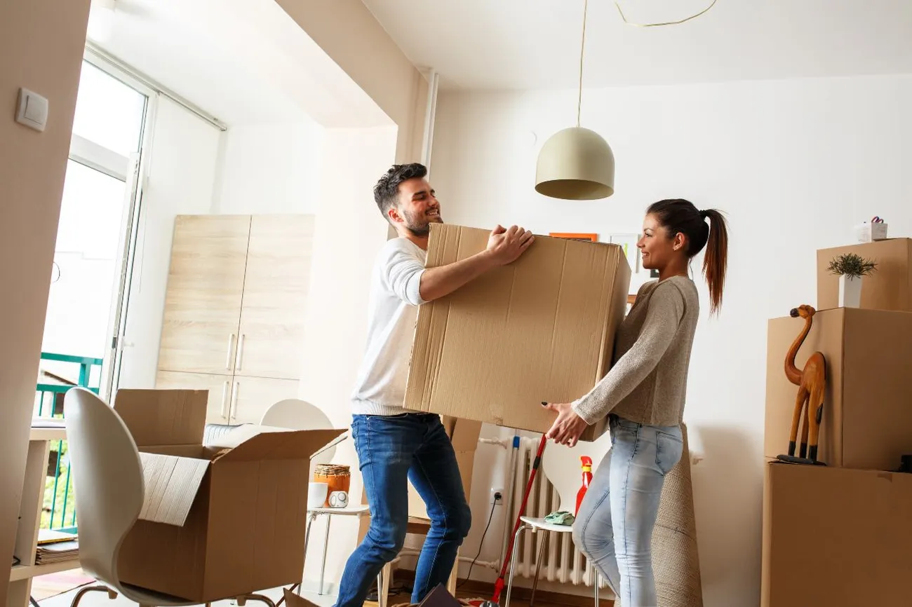 A young couple lifting a box in their new home