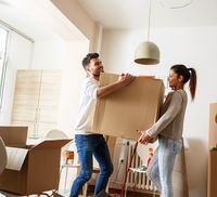 A young couple lifting a box in their new home