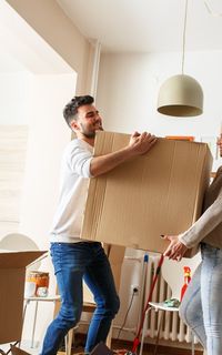 A young couple lifting a box in their new home