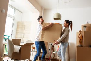 A young couple lifting a box in their new home