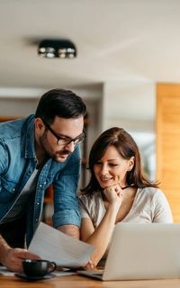 A young couple doing their finances on the laptop in their living room