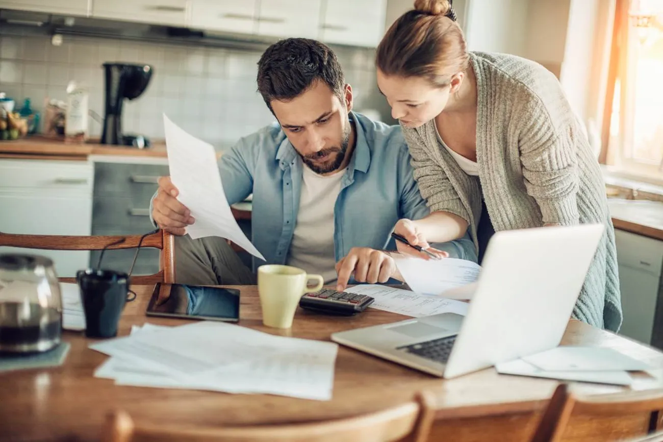 A couple looking at mortgage documents on their kitchen table as they consider to refinance