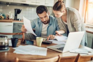 A couple looking at mortgage documents on their kitchen table as they consider to refinance